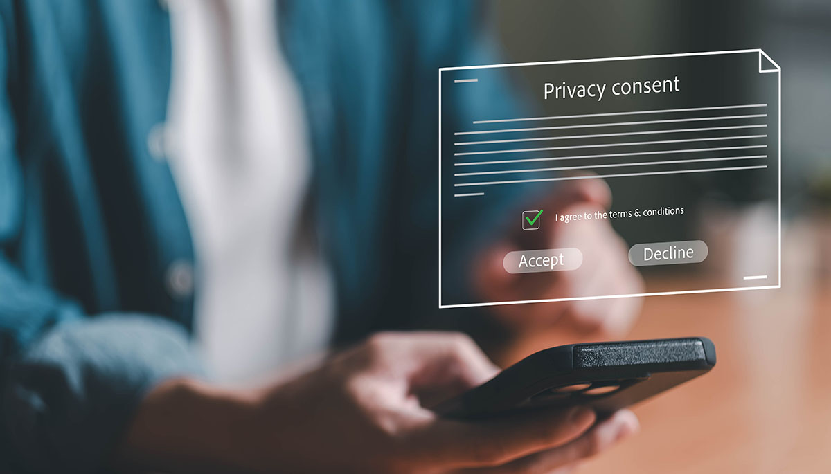 A hand holding a smartphone with a floating privacy consent dialog showing Accept and Decline buttons