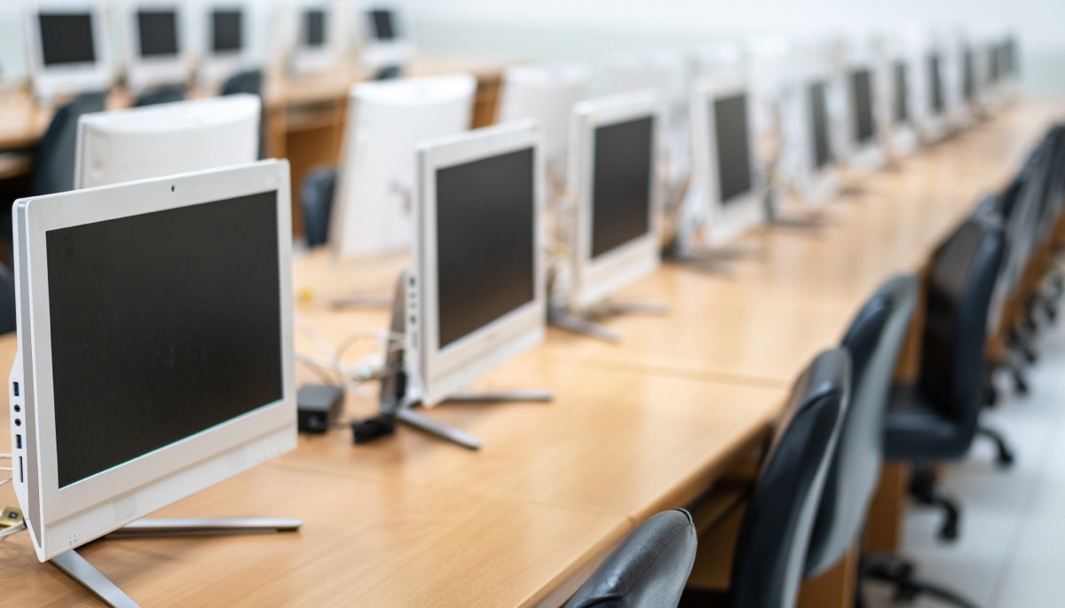 Rows of identical computer monitors in an empty office